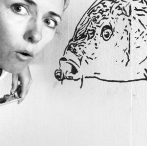 Artista MaDesi davanti a un suo Murale di un pesce carpa